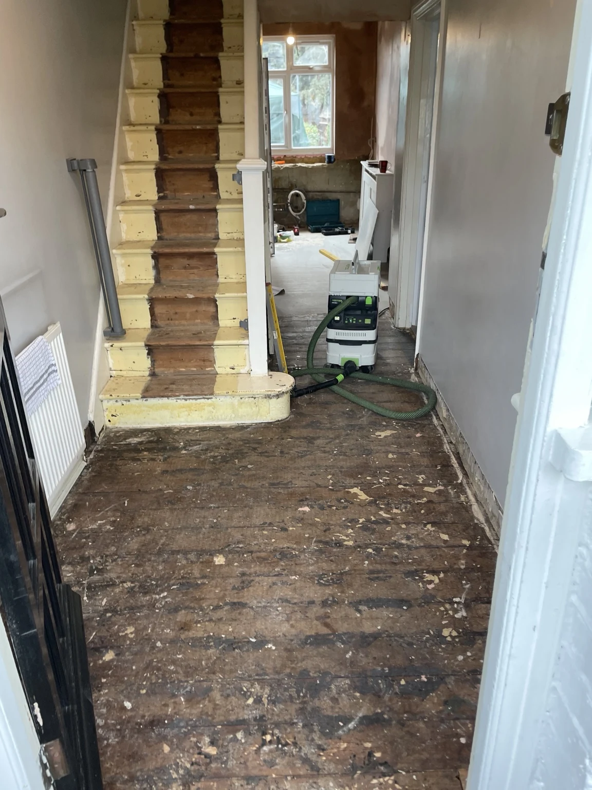 Stripped hallway floor beside staircase during refurbishment